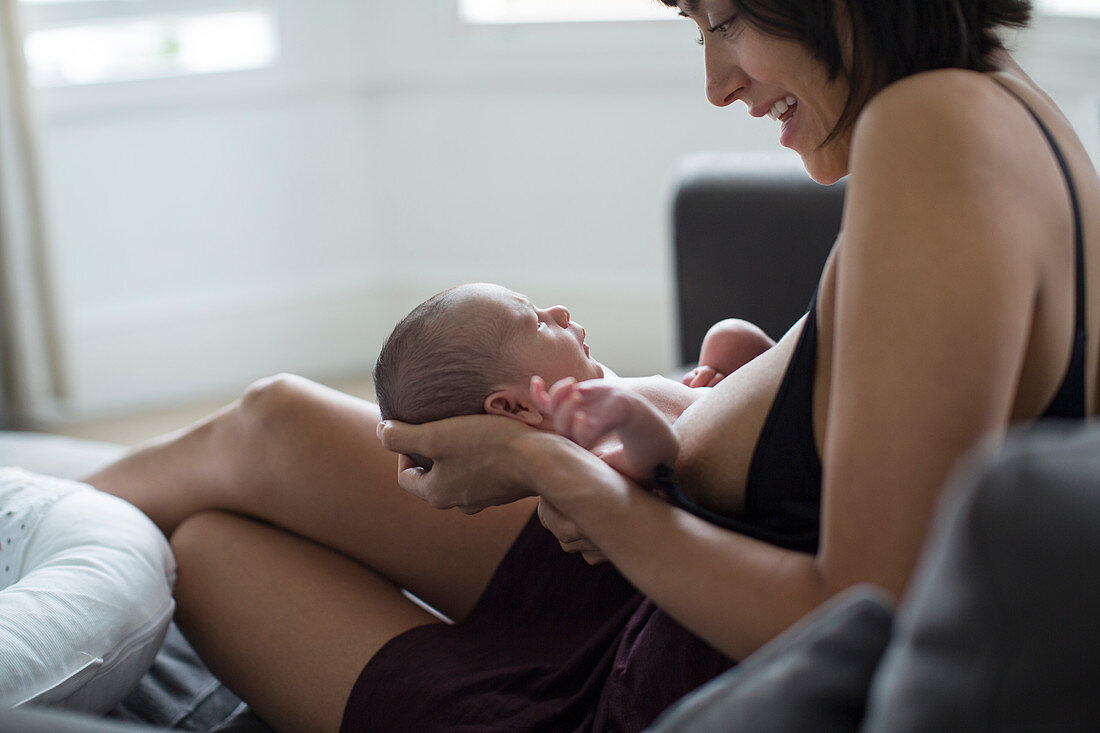 Mother holding and breastfeeding newborn baby son