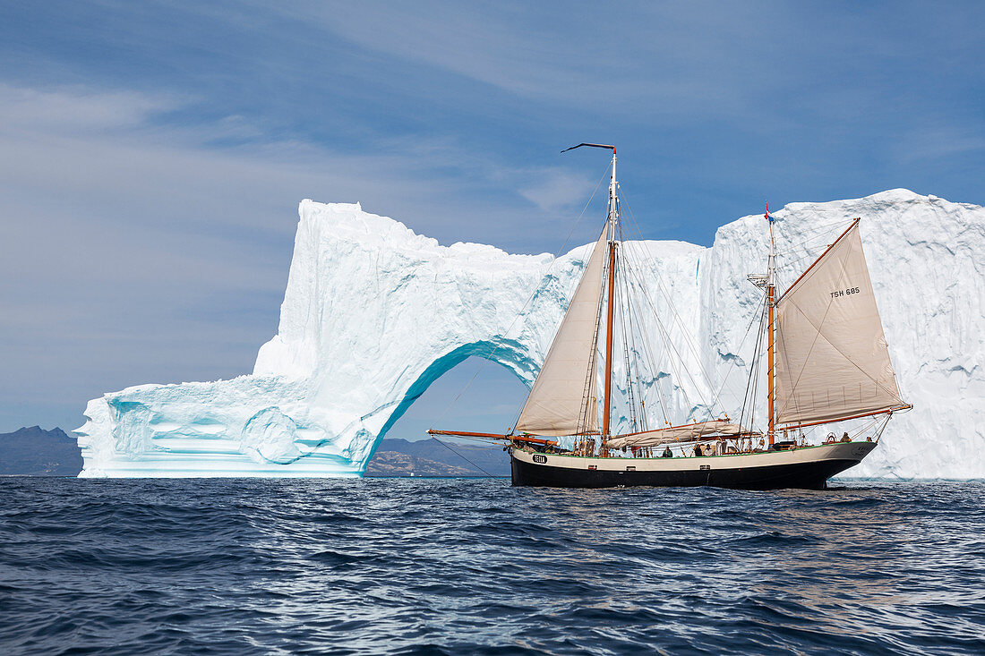 Ship moving toward iceberg arch on