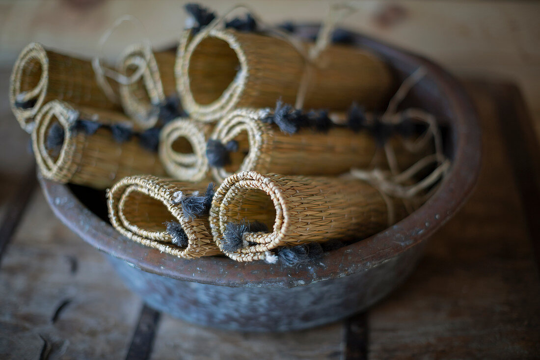 Rolled up rustic straw placemats in bowl
