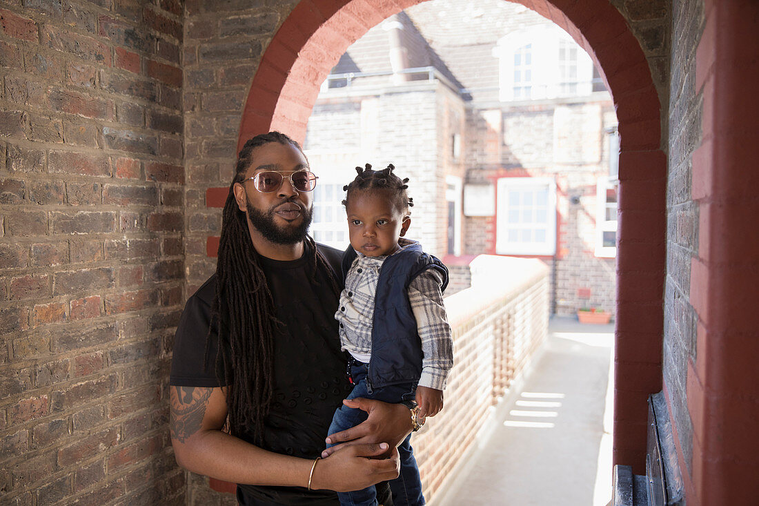 Portrait father holding toddler son in corridor archway