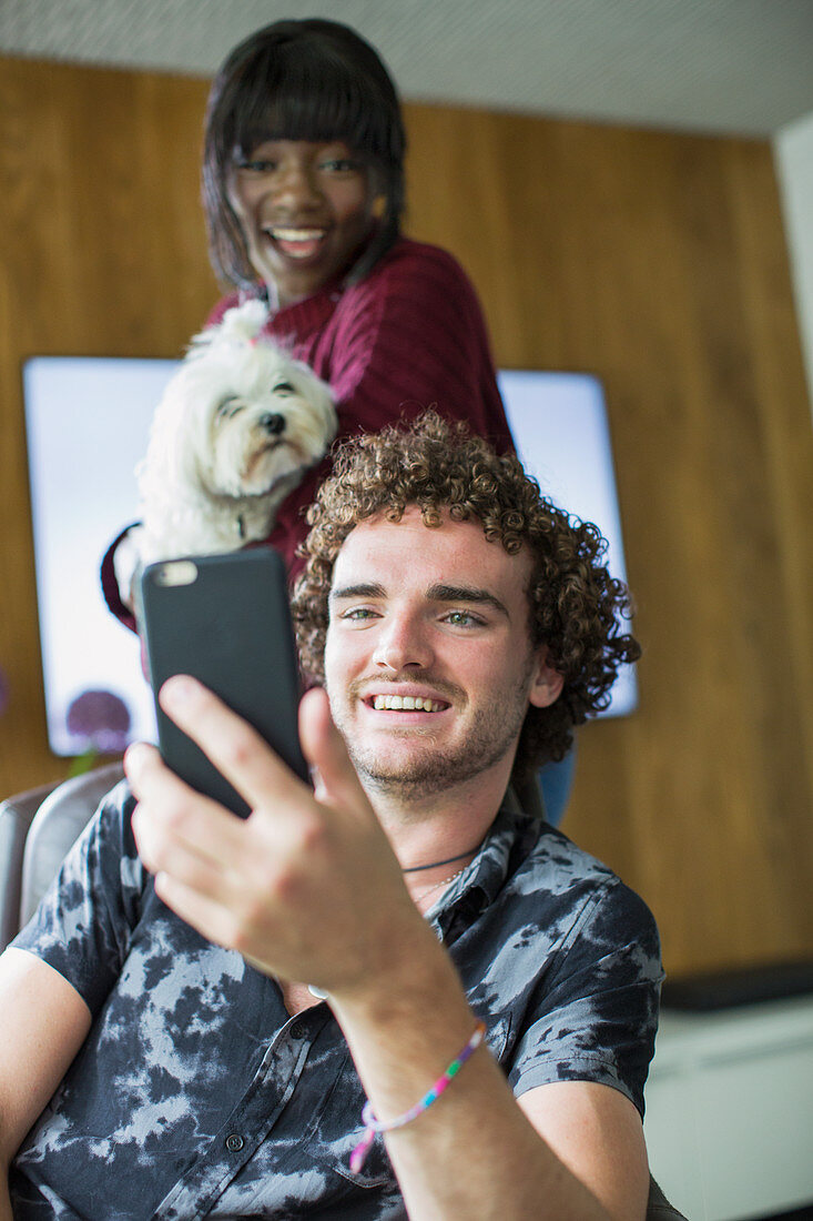 Happy couple with dog video chatting with smart phone