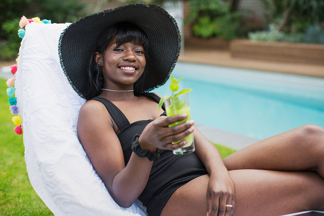 Portrait woman relaxing with cocktail at poolside
