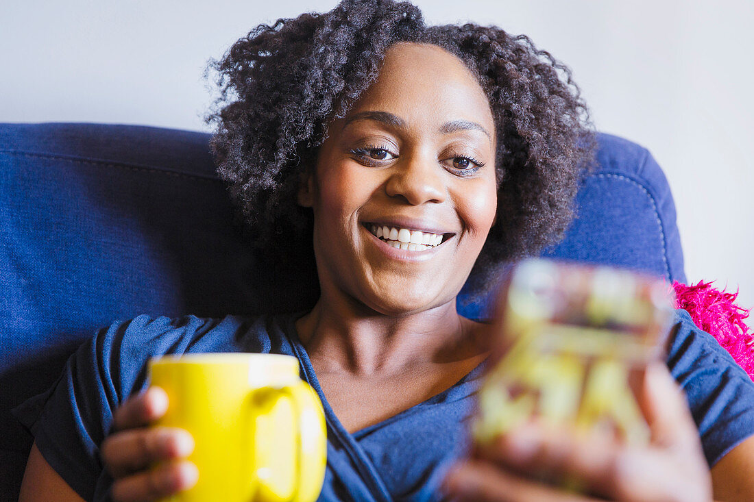 Close up woman drinking tea and using smart phone