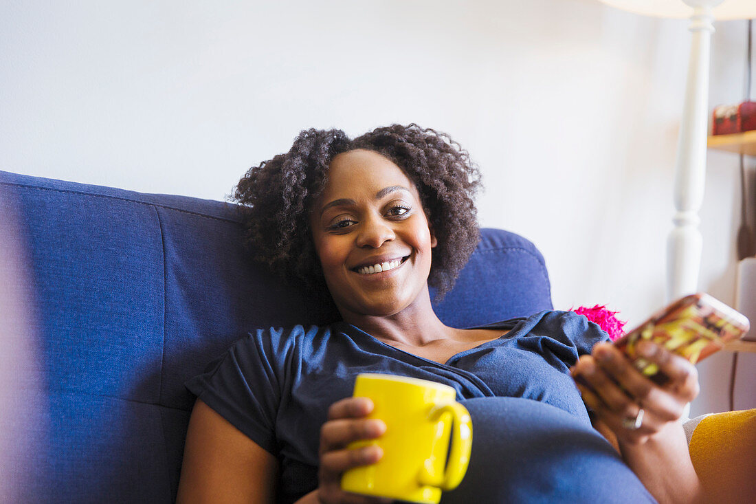 Portrait pregnant woman drinking tea and using smart phone