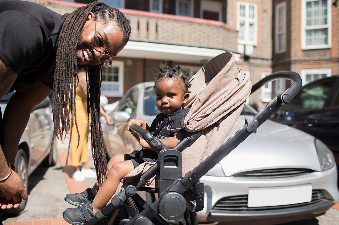 Father with long braids and toddler son in stroller
