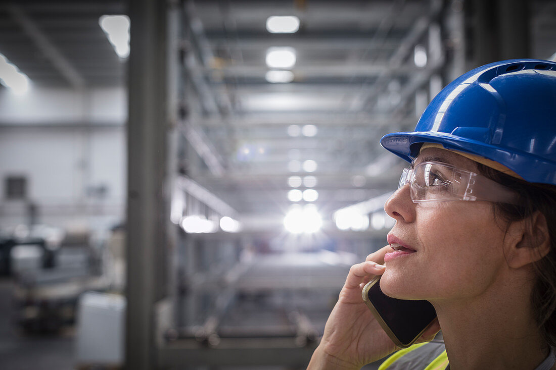 Female worker talking on cell phone in factory