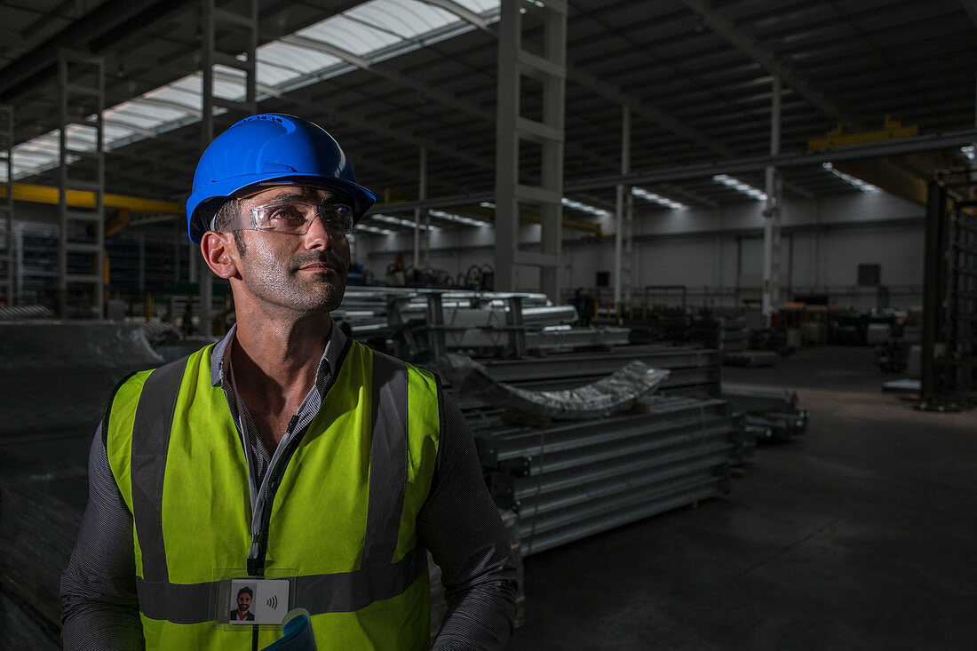 Portrait confident male worker looking away in dark factory