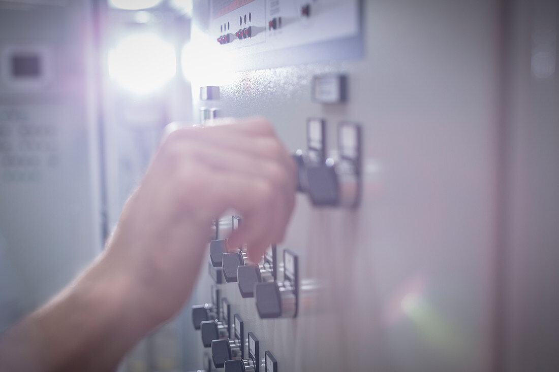 Close up hand adjusting knob at control panel in factory