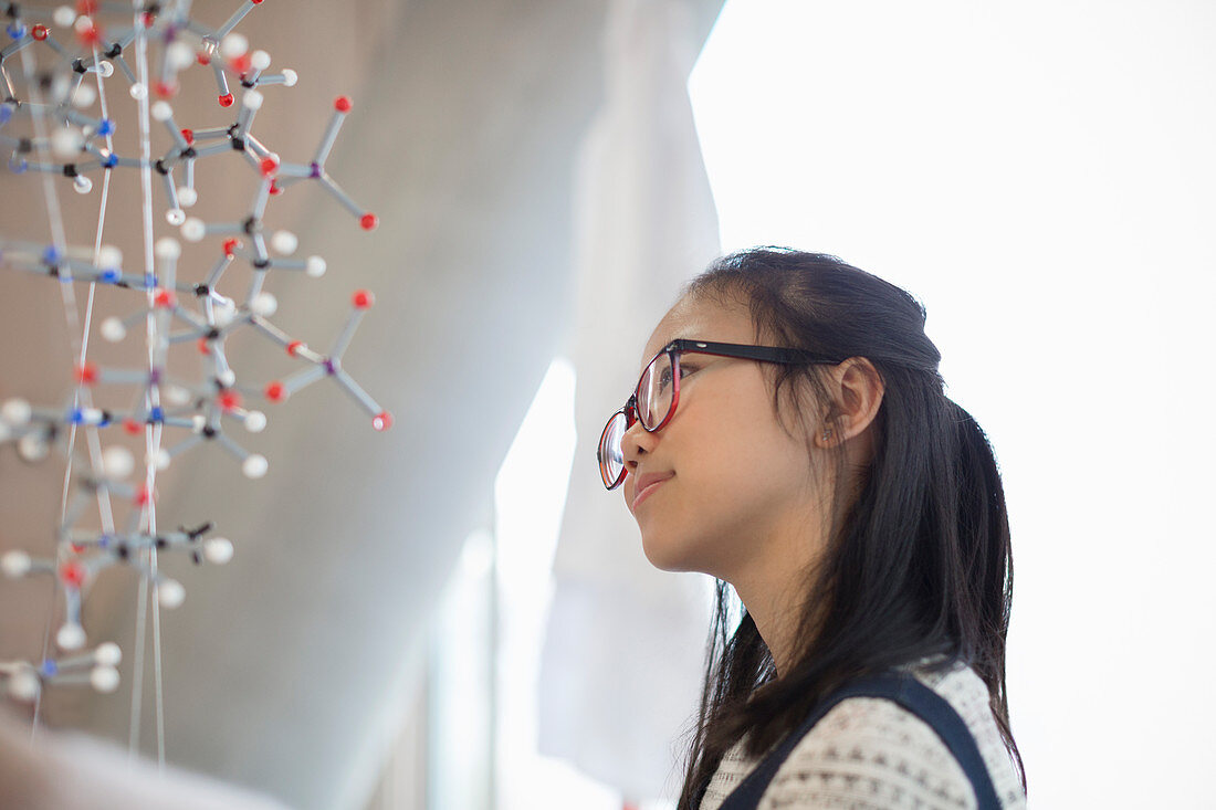 Pensive, curious girl student examining molecular structure