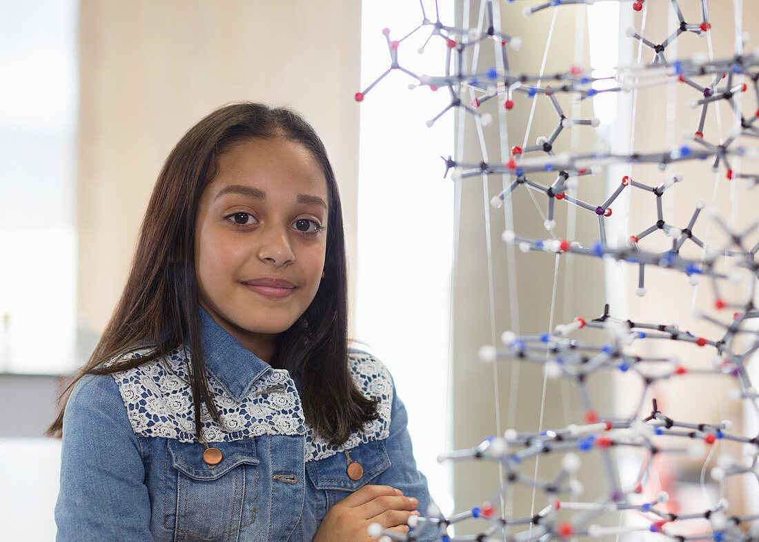 Girl student next to molecular structure in classroom