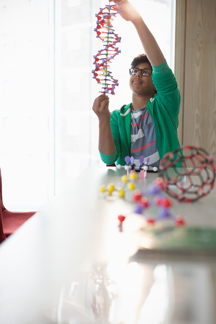 Boy student examining DNA model in laboratory classroom