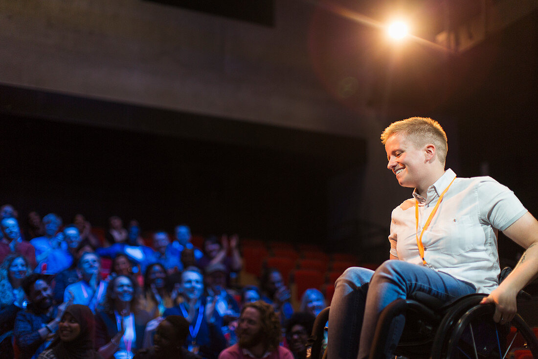 Smiling female speaker in wheelchair on stage