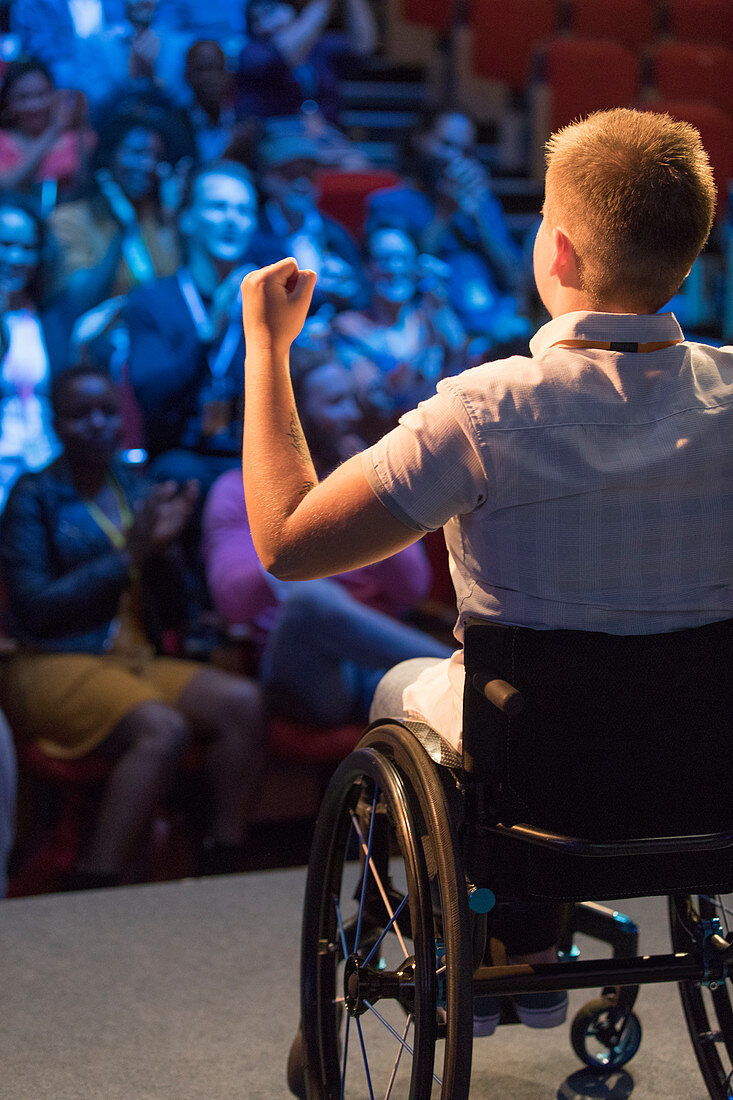 Female speaker in wheelchair gesturing for cheering audience