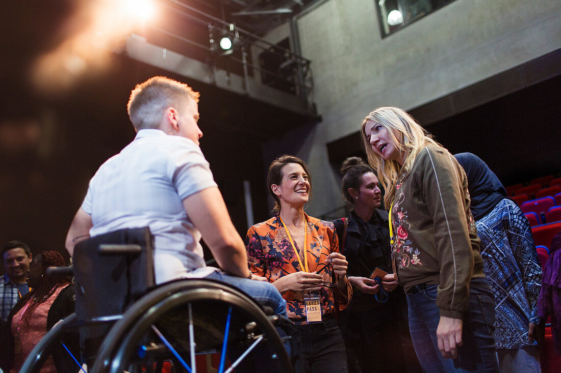 Women in conference talking to speaker in wheelchair