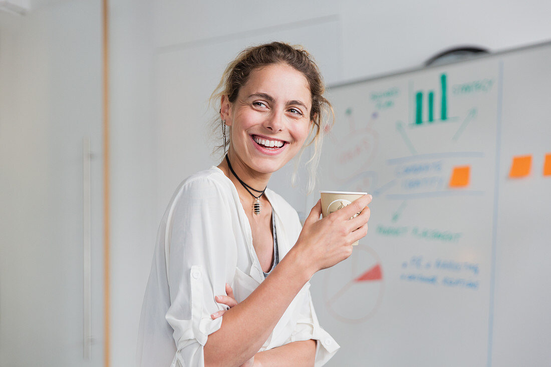 Smiling businesswoman drinking coffee in conference room