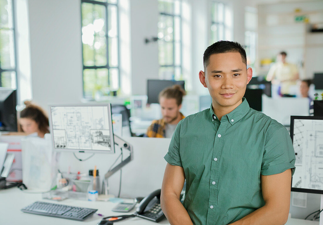 Portrait confident male architect in open plan office