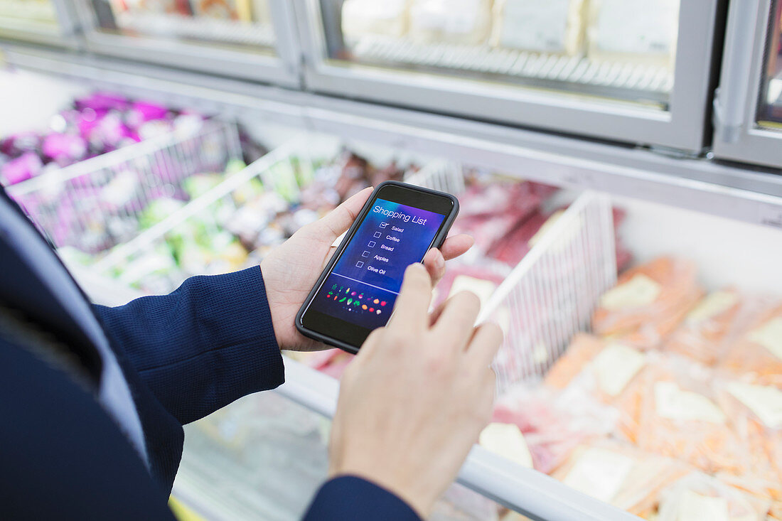 Woman using shopping list app, shopping in supermarket