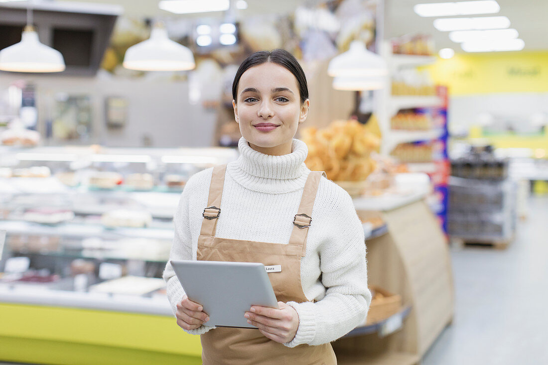 Female grocer with tablet working in supermarket