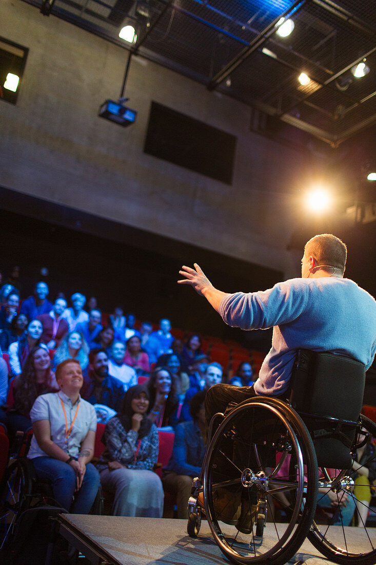 Audience watching male speaker in wheelchair talking