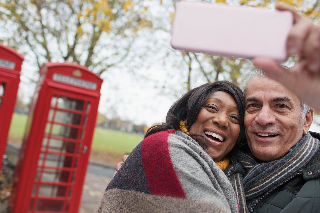 Couple taking selfie in park in front of red telephone book