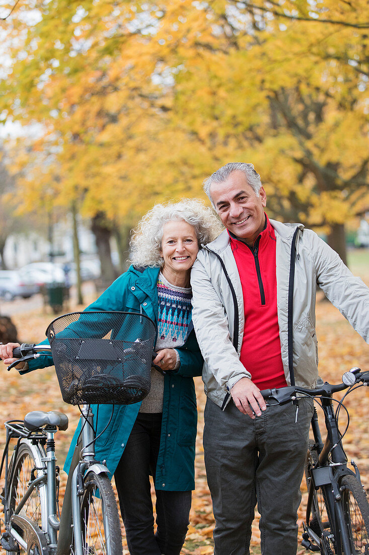 Carefree senior couple with bicycles in autumn park