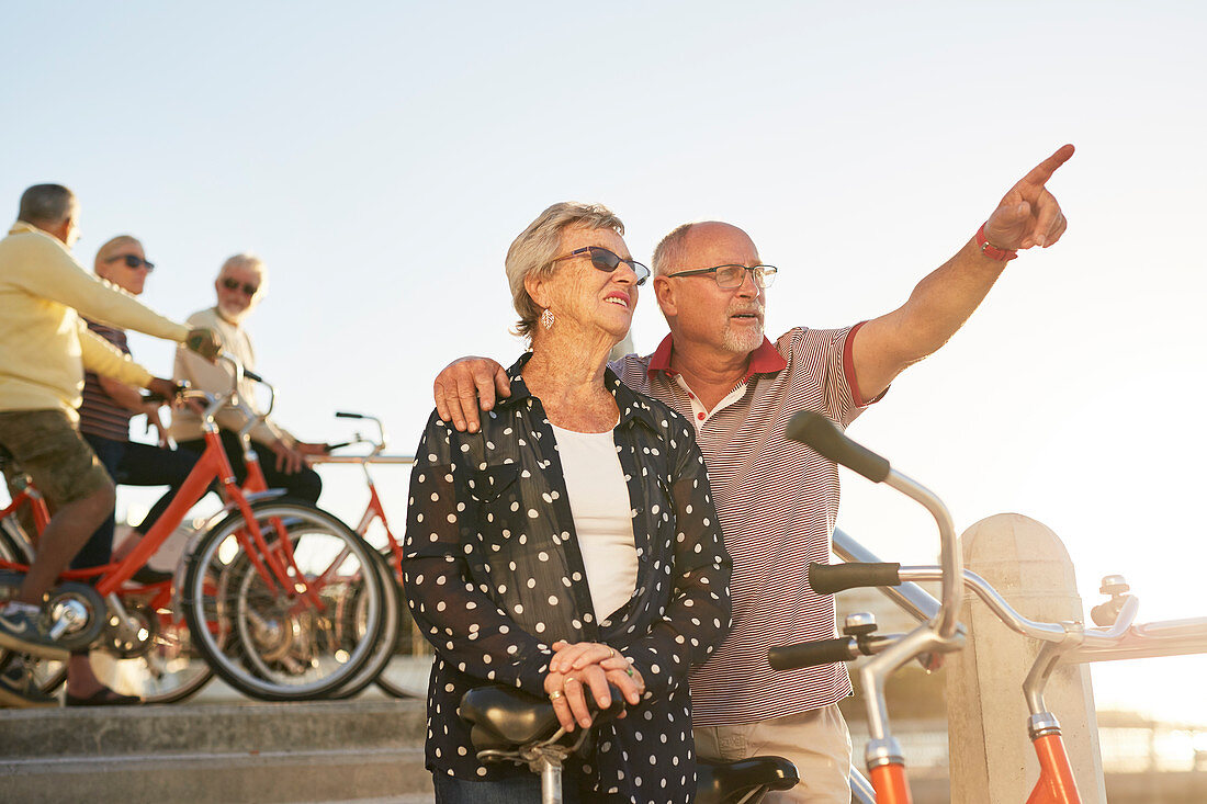 Active senior couple tourists with bicycles looking at view