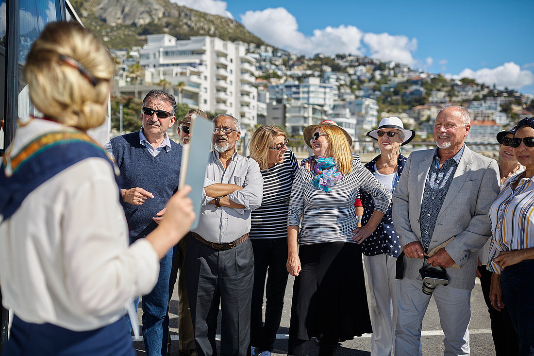 Active senior tourist friends listening to tour guide