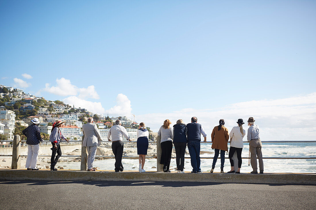 Active senior tourist friends looking at sunny ocean view