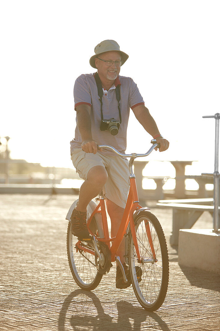 Active senior man tourist bike riding on sunny boardwalk