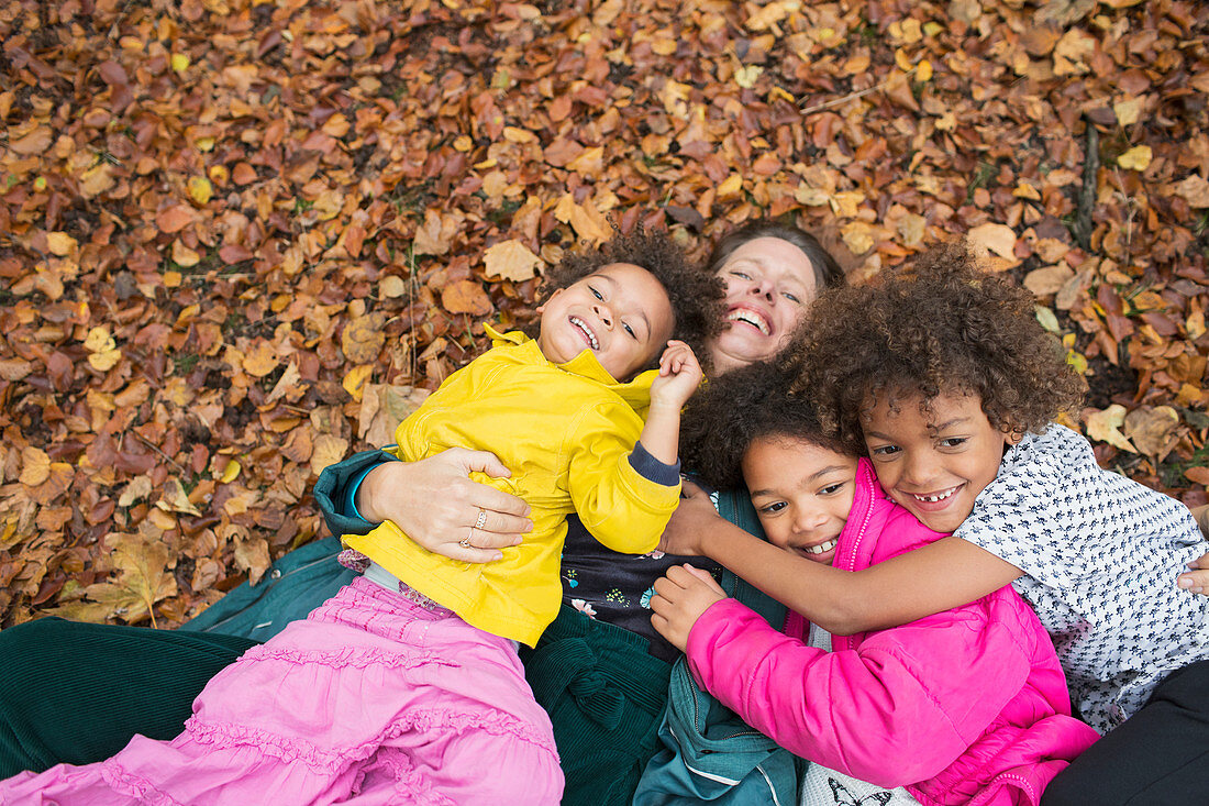 Portrait happy mother and children laying in autumn leaves