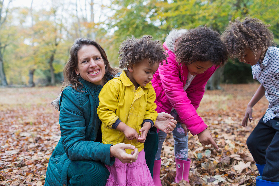 Portrait happy mother and children playing in autumn leaves