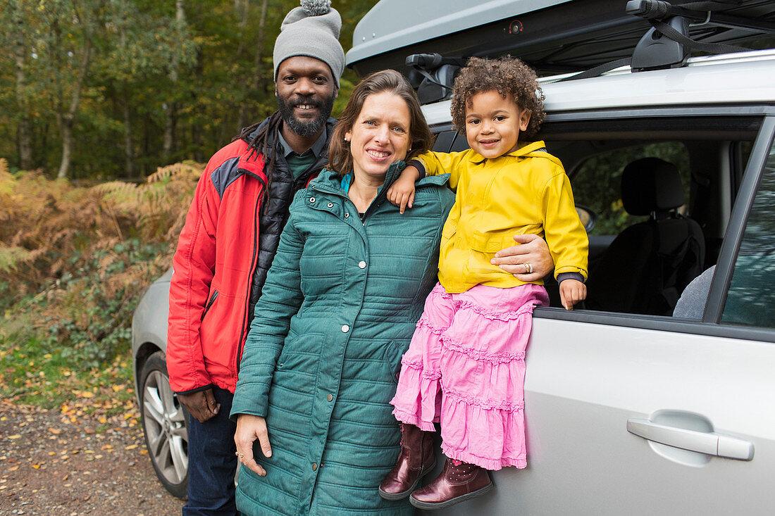 Portrait happy parents and toddler daughter outside car