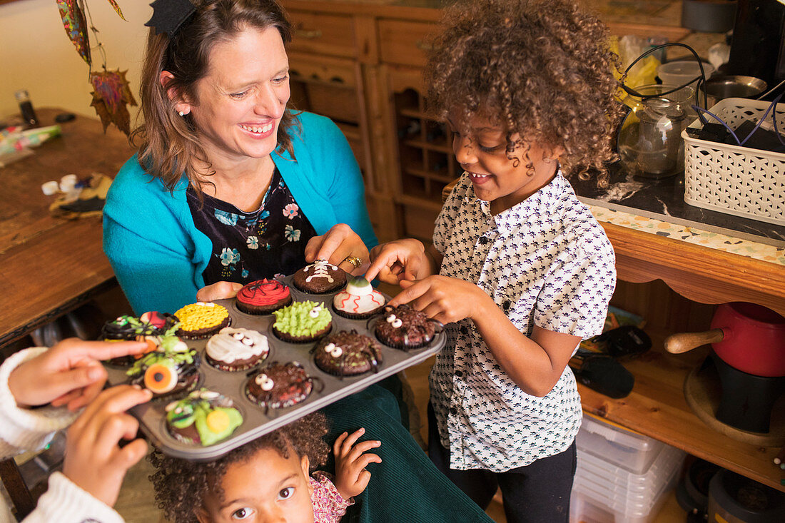 Happy mother and children with decorated Halloween cupcakes