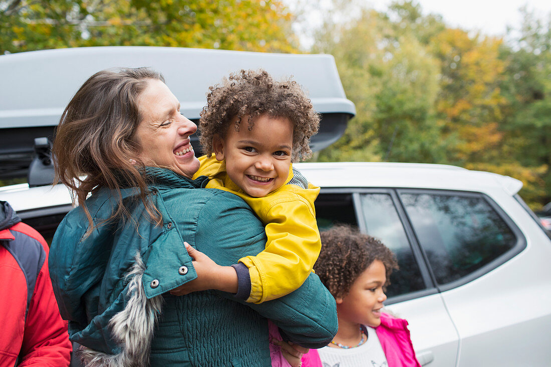 Happy mother holding daughter outside car in parking lot