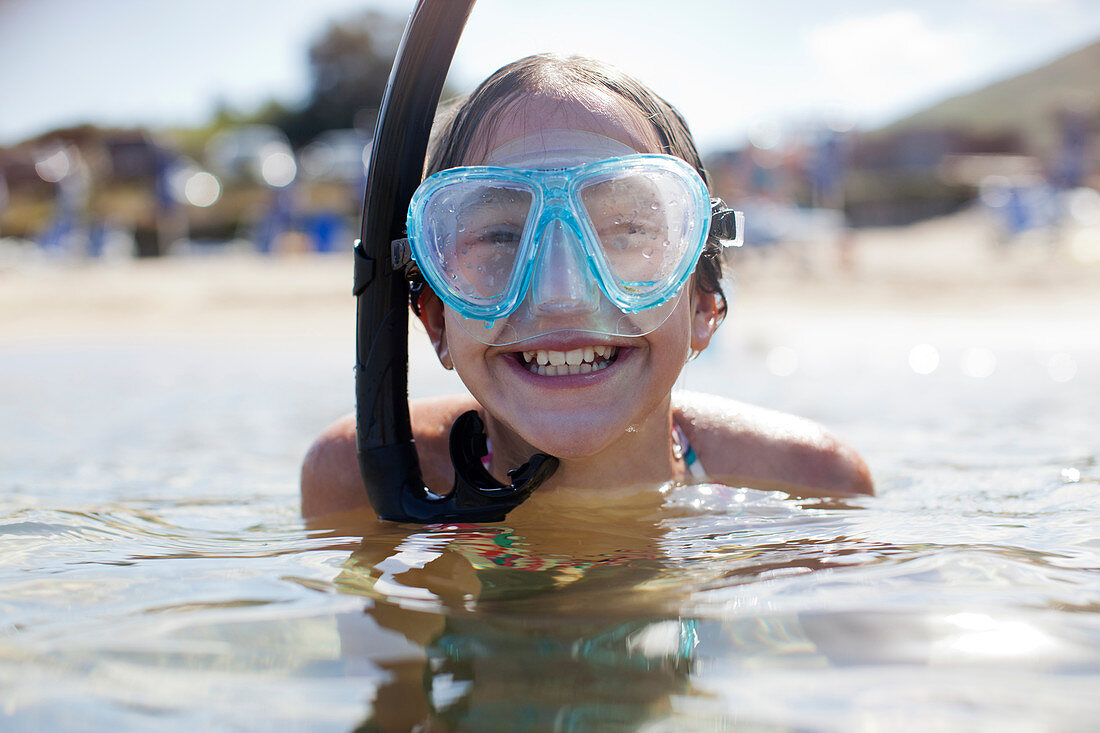 Happy girl wearing snorkel and goggles in ocean