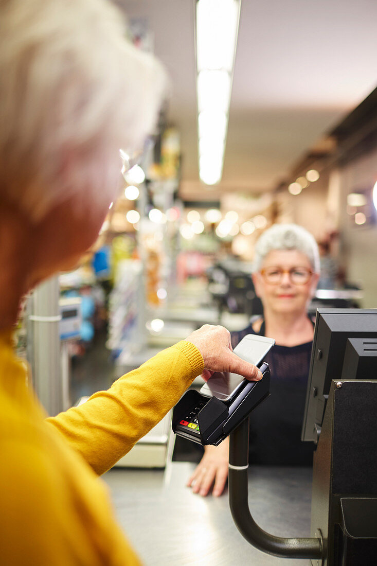 Customer paying with smart phone at supermarket checkout