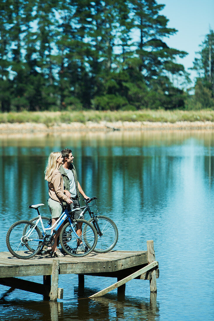 Couple with bicycles on dock overlooking lake
