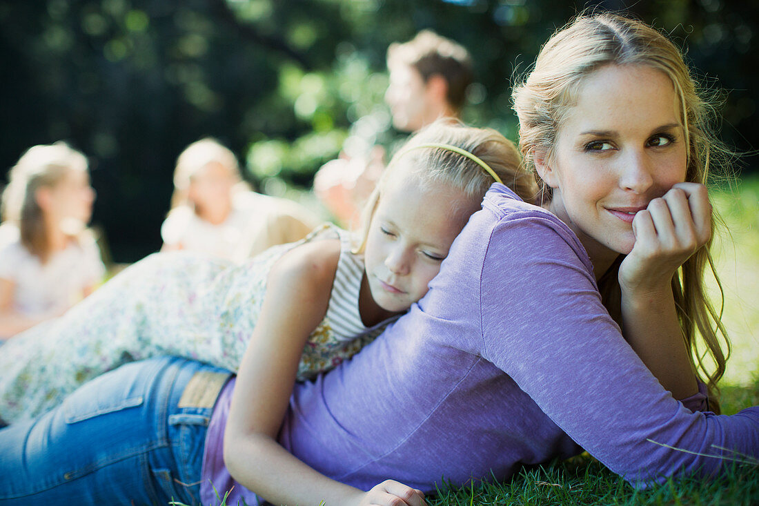 Serene mother and daughter laying in grass