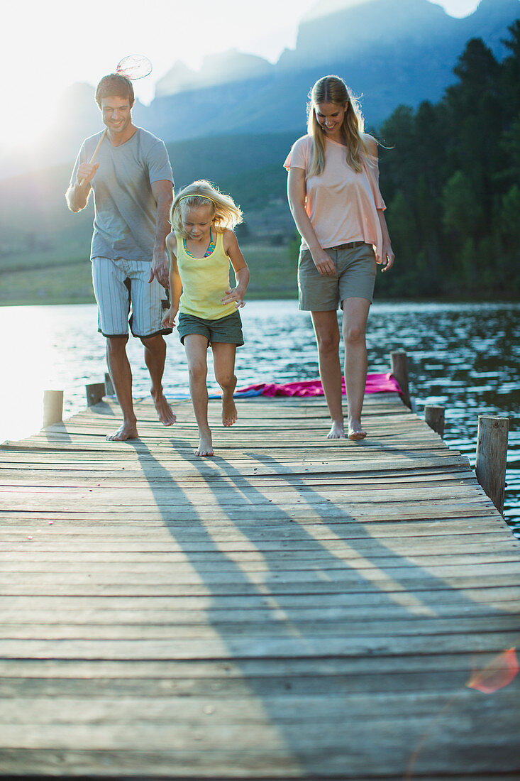 Family running on dock over lake