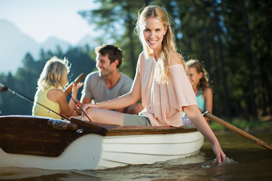 Smiling woman with family in rowboat on lake