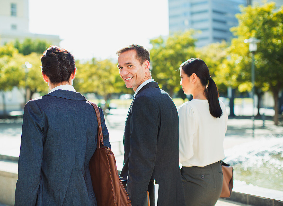 Smiling businessman walking with colleagues outdoors