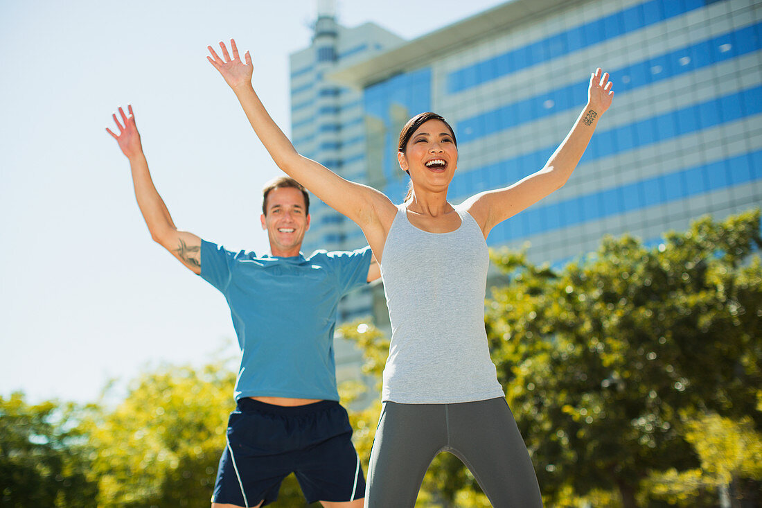Enthusiastic couple exercising in urban park