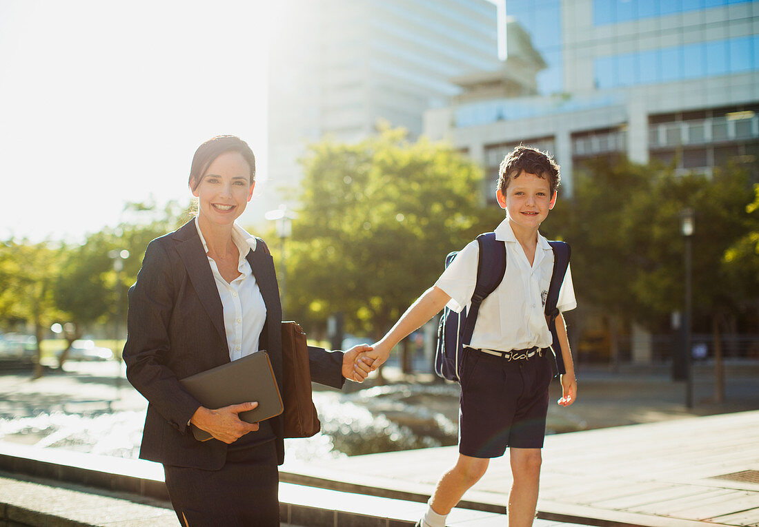 Smiling businesswoman walking with son outdoors