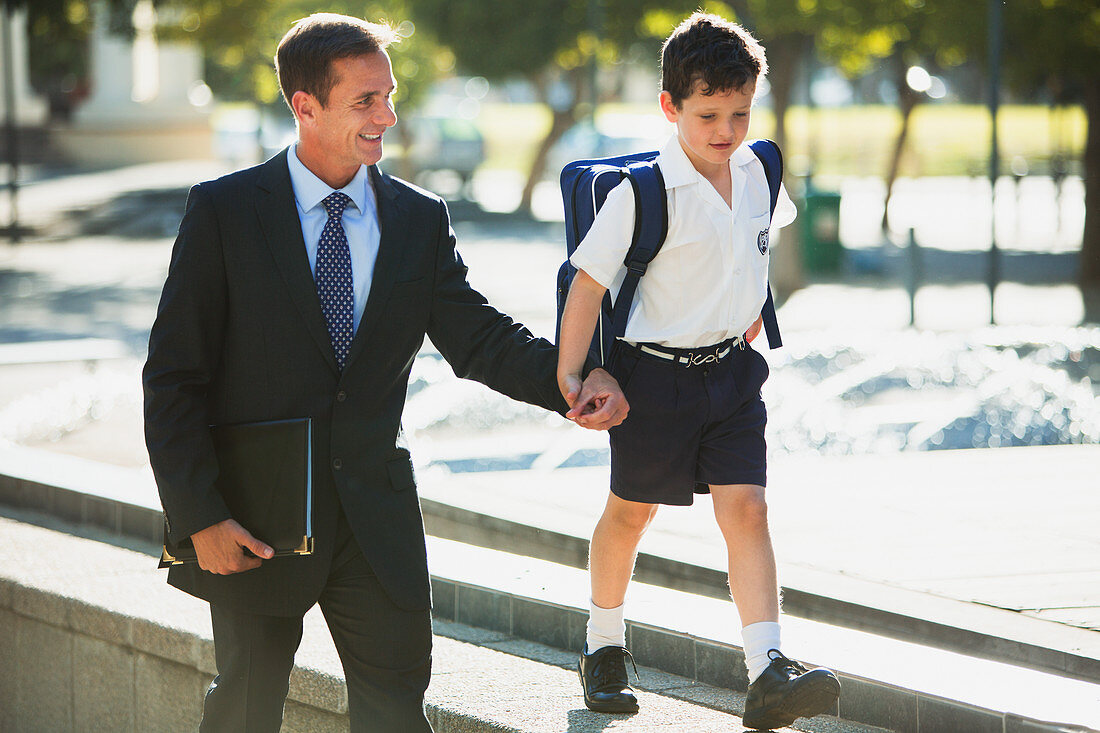 Businessman and son holding hands in urban park