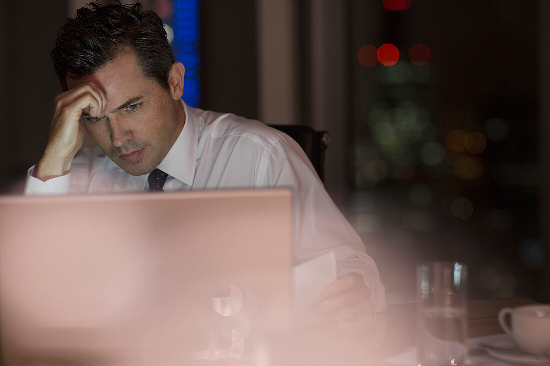 Stressed businessman working late at laptop in office