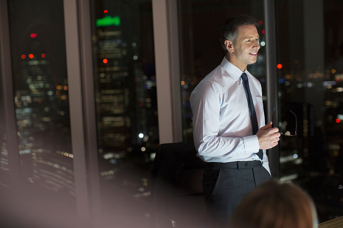 Businessman smiling in office at night
