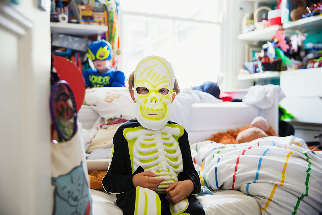 Boy sitting on bed in his room dressed in skeleton costume