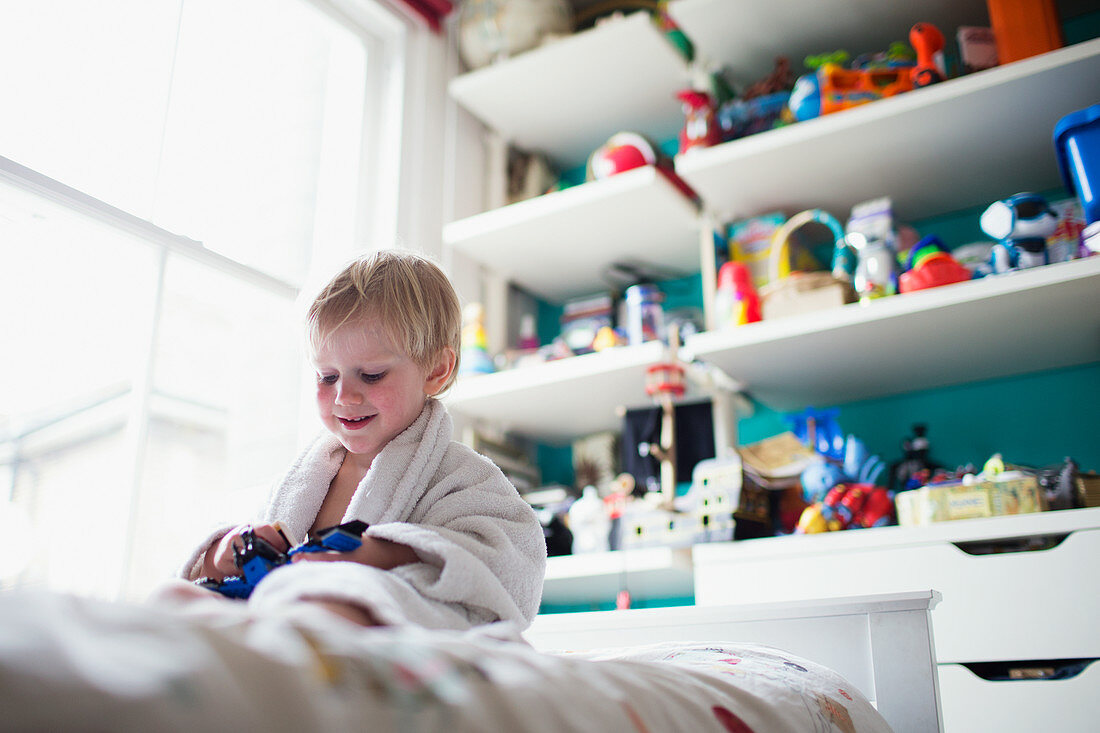 Boy sitting in bed in his room playing with toy