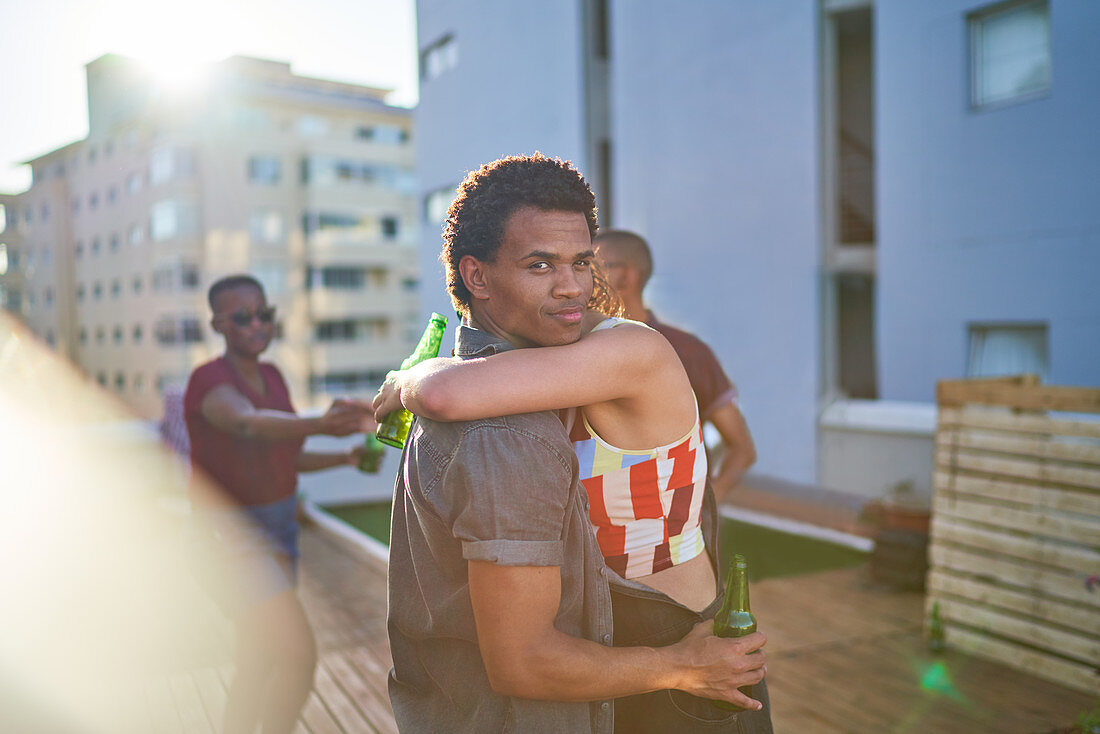 Young couple hugging and drinking beer on urban rooftop