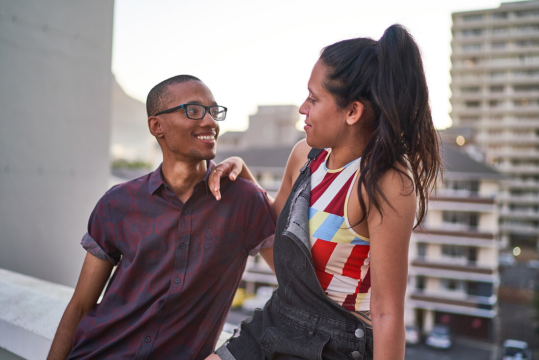 Happy young couple talking on urban rooftop balcony